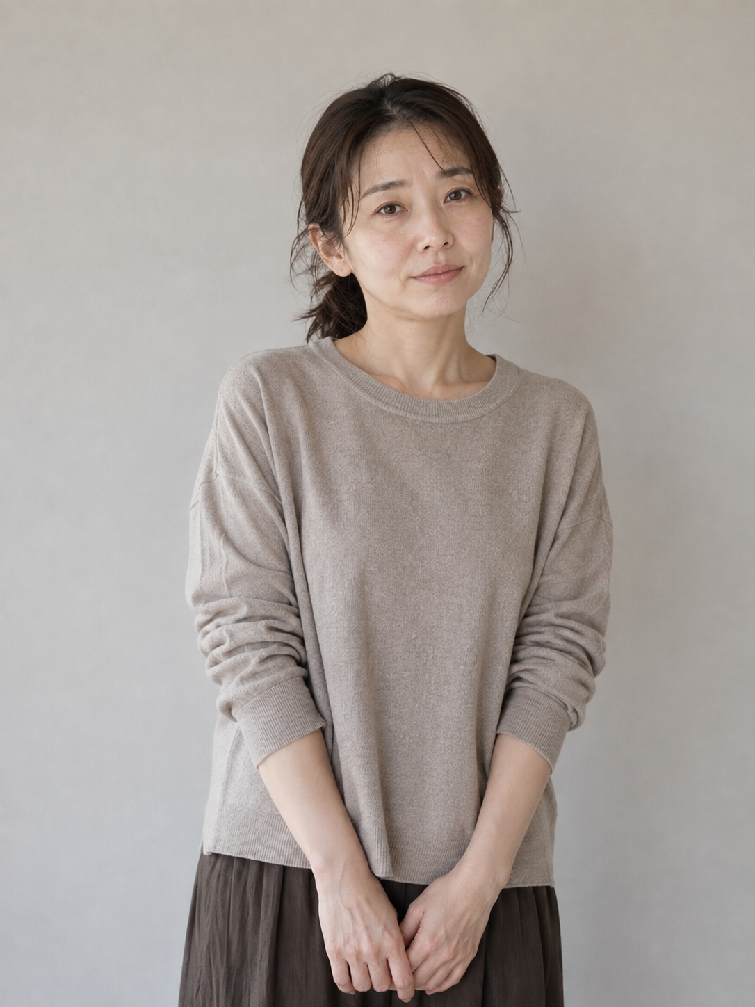 印象プロデュース前のベージュのトップスで髪を束ねた女性